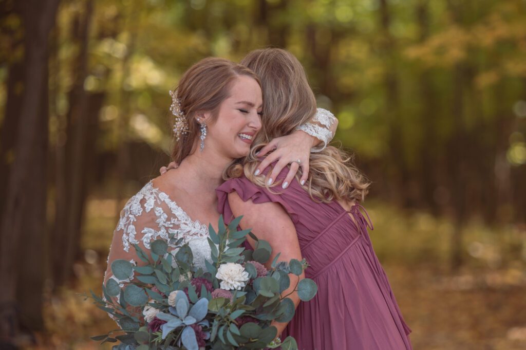 An image of a bride crying while hugging one of her bridesmaids on her wedding day