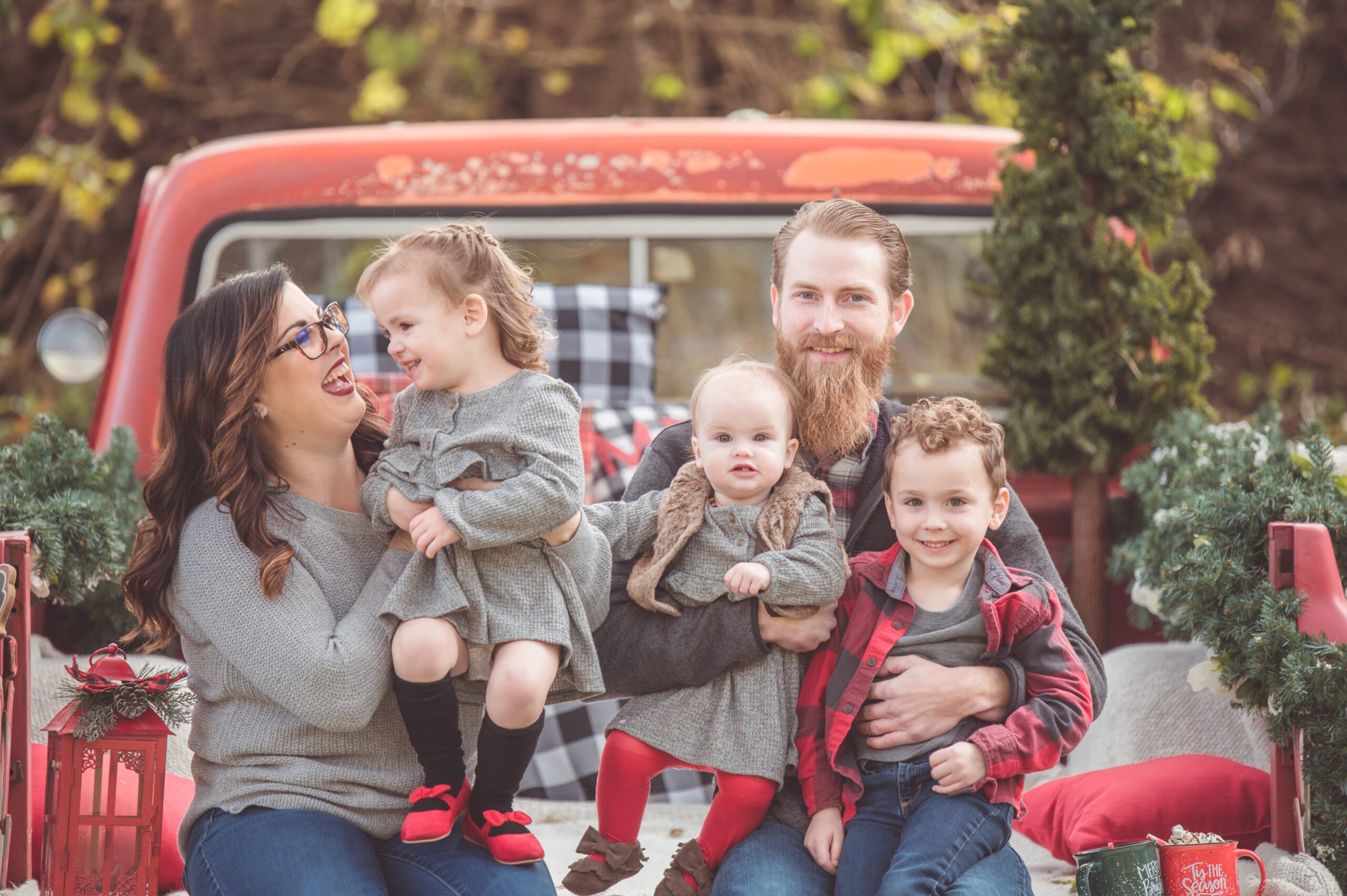 Christmas Mini Session Photo of a Family on a Red Truck in White Lake, Michigan.